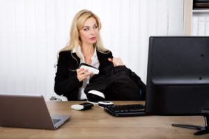 Close-up Of A Businesswoman Stealing A Stapler At Office Desk